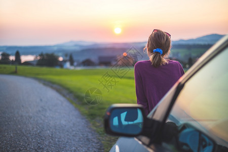 年轻女士坐在车里享受日落图片