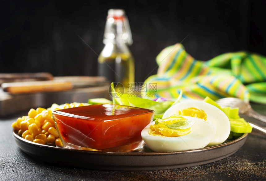 盘子上的沙拉加软煮蛋液体黄玉米卷心菜黄瓜番茄酱图片