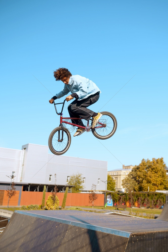 骑马的男子在坡道上耍花招参加滑板场训练的少年极端自行车运动危险的自行车运动危险的街头骑车在夏季公园骑自行车在滑板场上玩花样的男子图片