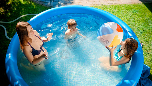 与期一会快乐的家庭在户外游泳池与充气海滩球玩得开心的家庭快乐暑假和期概念快乐家庭与充气海滩球在户外游泳池的乐趣快暑假和期概念背景