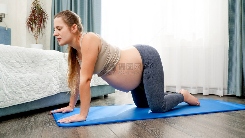 怀孕期间健康的生活方式保健和运动概念怀孕期间美丽的妇在卧室健身垫上拉和做瑜伽练习怀孕期间健康的生活方式保健和运动概念图片