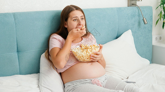 吃爆米花的女孩口吃爆米花用大碗的手抓住它贪食和过度欲的概念口吃和过度食欲的概念口吃和过度食欲概念背景