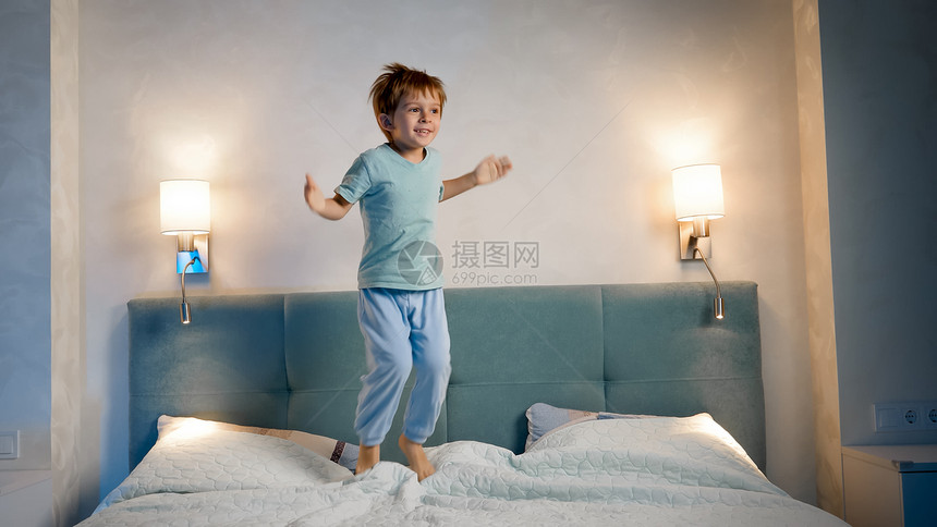 快乐笑和的幼儿男孩穿着睡衣跳上父母和睡前晚上床快乐笑和的幼儿男孩穿着睡衣跳上父母和睡前晚上床图片