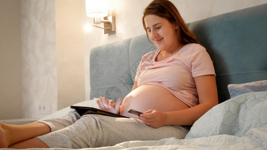 孕妇晚上在床上使用平板电脑图片
