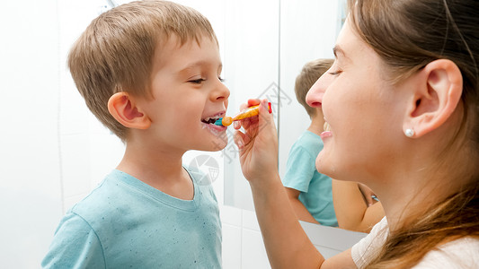 幼儿保育母亲为其小儿子刷牙和父母儿童照顾牙齿健康和卫生父母儿童照顾牙齿健康和卫生背景图片