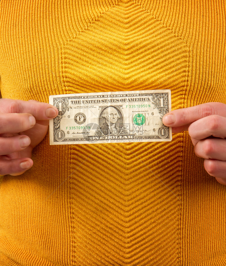 一个穿着黄毛衫的男人拿着一块钱的钞票图片