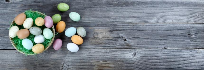 复活节快乐概念左边是一篮子在生锈木板上流来多彩的鸡蛋和绿草上流来去的一篮多彩蛋和绿草图片