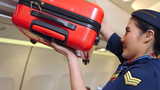 航空空姐在帮助乘客放行李箱图片