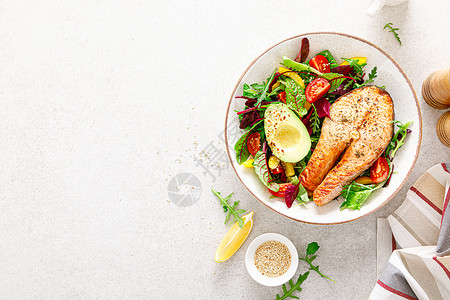 鲑鱼牛排烧烤鳄梨和新鲜蔬菜沙拉配有番茄铃椒和叶蔬菜背景图片