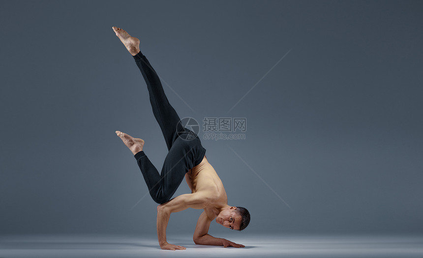 男瑜伽让巴朗人举起手来很困难灰色背景强健的人在做瑜伽练习麻培训高度集中健康的生活方式男瑜伽让巴朗人举起手来很困难图片