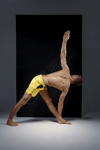 运动瑜伽在工作室进行伸展运动灰色背景强壮的人在工作室进行伸展运动图片