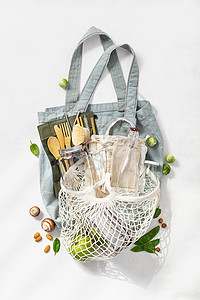 网格袋装有棉花袋玻璃罐子和竹制餐具的无塑料袋零废物生态友好型购物概念背景
