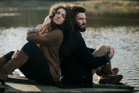 情人背靠背坐在湖边的码头上图片