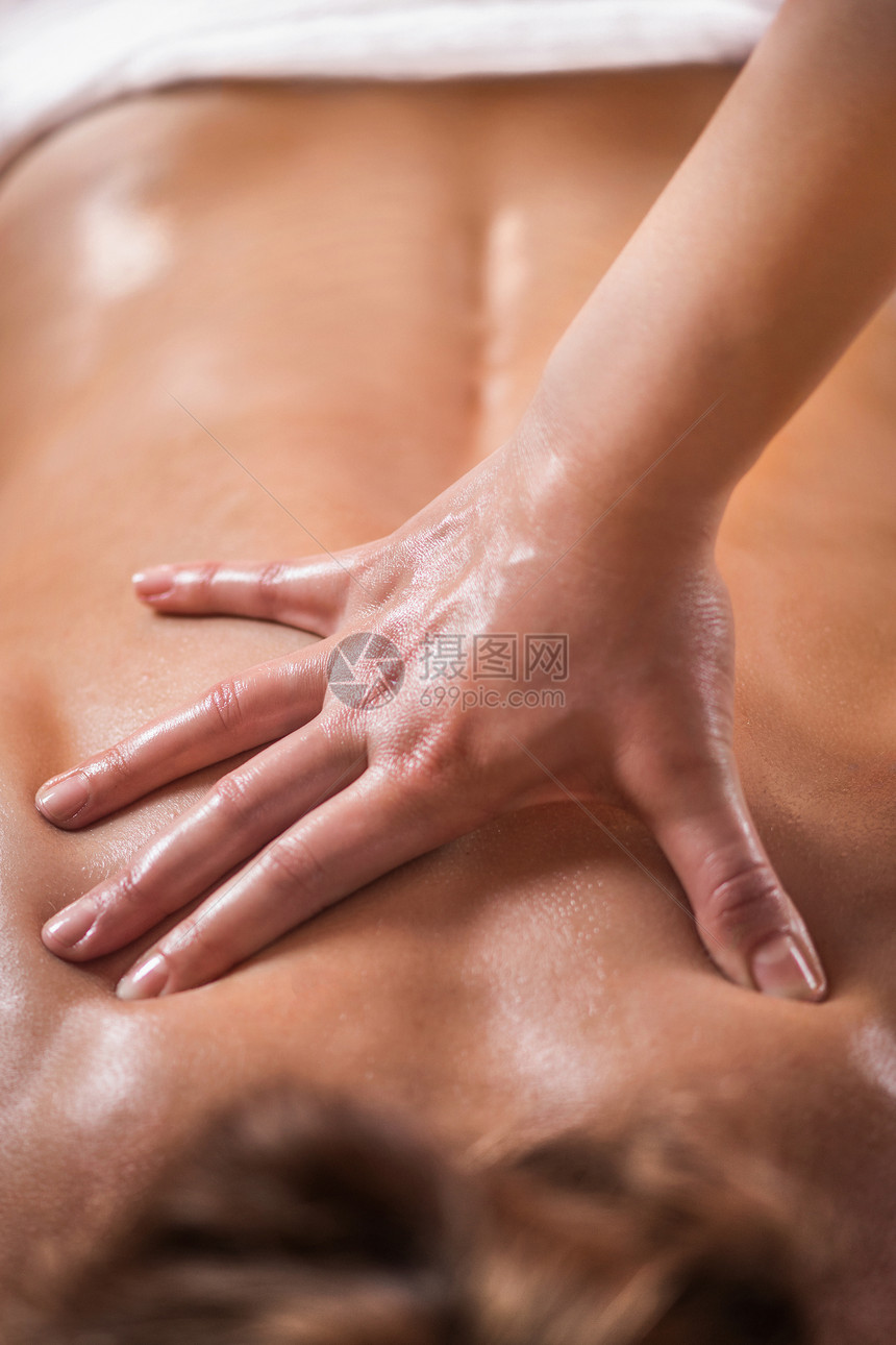 生理治疗师对背部肌肉受伤的女病人进行按摩的近距离图像图片