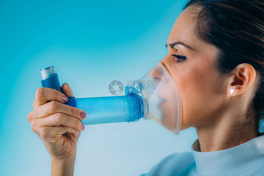妇女使用带有扩展管的Asthma吸入器图片