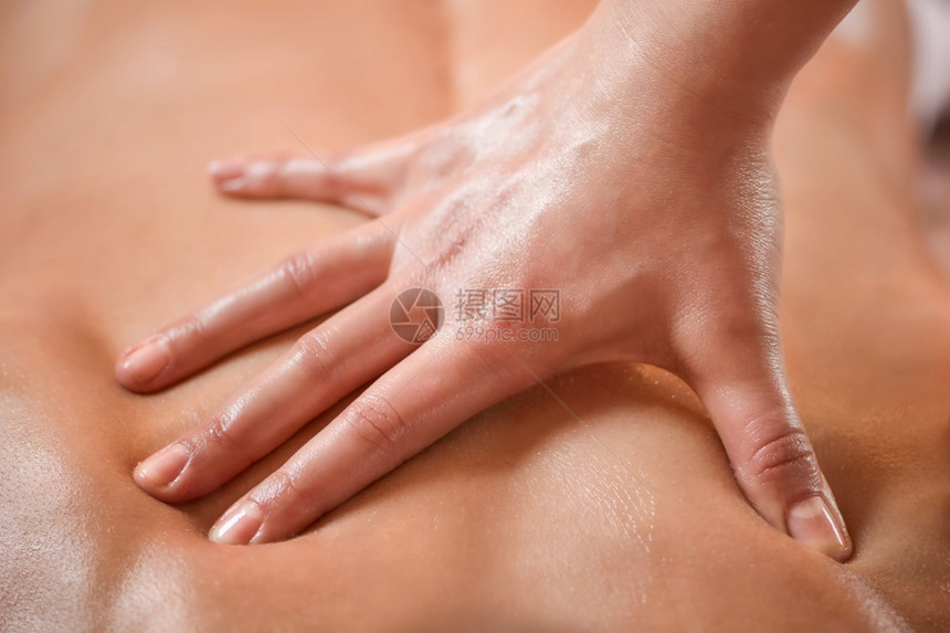 生理治疗师对背部肌肉受伤的女病人进行按摩的近距离图像图片