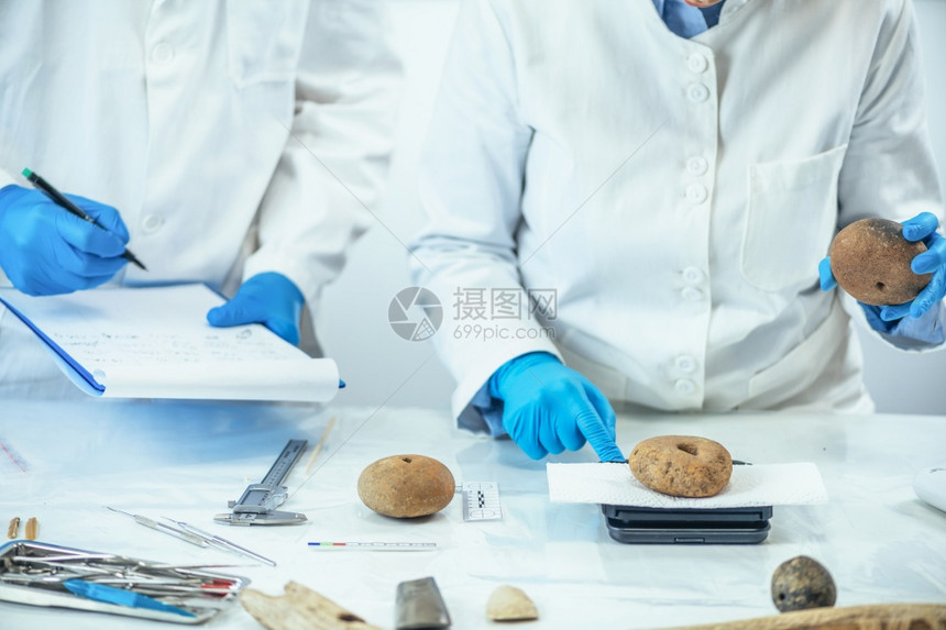 考古学家测量老文物在实验室数字尺度上用于渔网测量的古代文物在实验室中的织物重量或考古学家测量实验室精密尺度上的史前体重图片