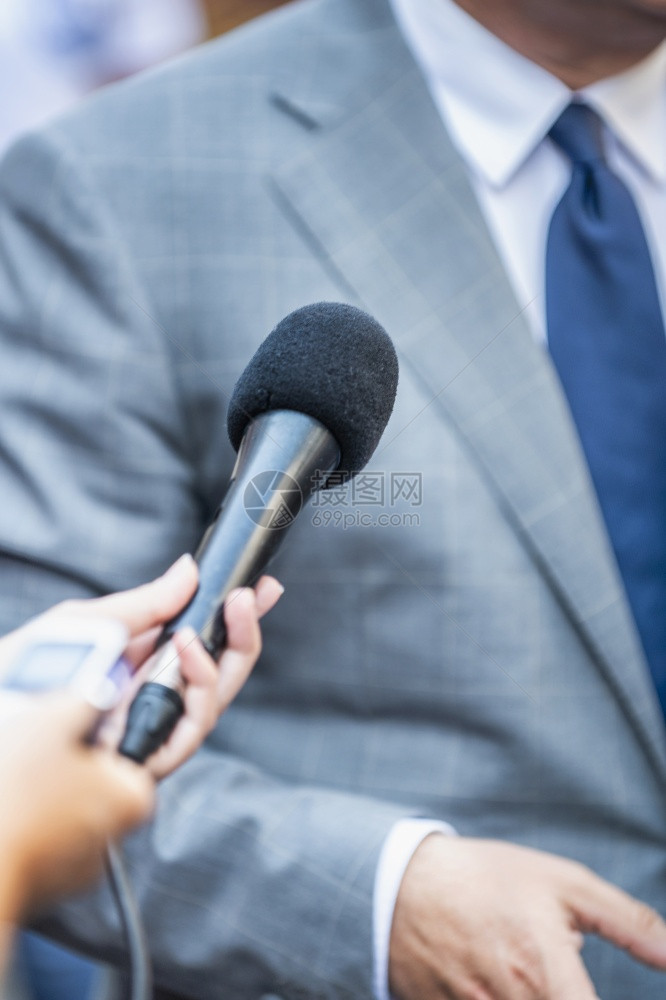 媒体采访记者用麦克风采访身着正式服装的政治家或商人图片
