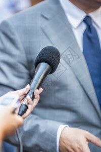 媒体采访记者用麦克风采访身着正式服装的政治家或商人图片