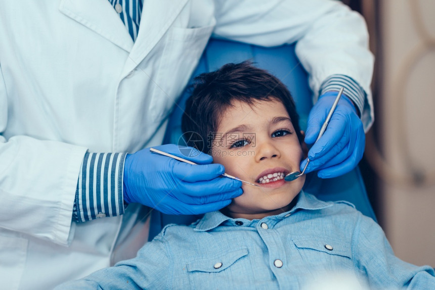 牙医对小男孩定期进行牙科检查图片