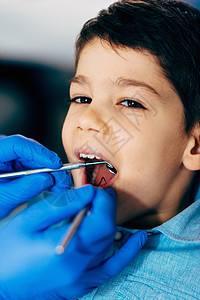 工具地方牙医对小男孩定期进行牙科检查背景