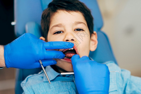 牙医对小男孩定期进行牙科检查图片