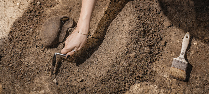 挖掘工具考古学家用手表挖掘从考古遗址中回收老陶器背景