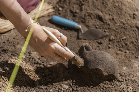 考古工具在考古遗址挖掘老陶器文物的女考古学家背景