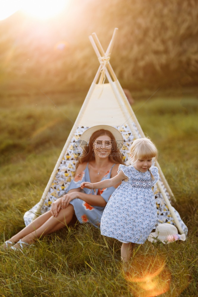 美丽的母亲与女儿坐在田野的假发旁与女儿一起度过时间在外面度假户美丽的日落光照在花园或公美丽的母亲与女儿坐在田野的假发光照下美丽的图片
