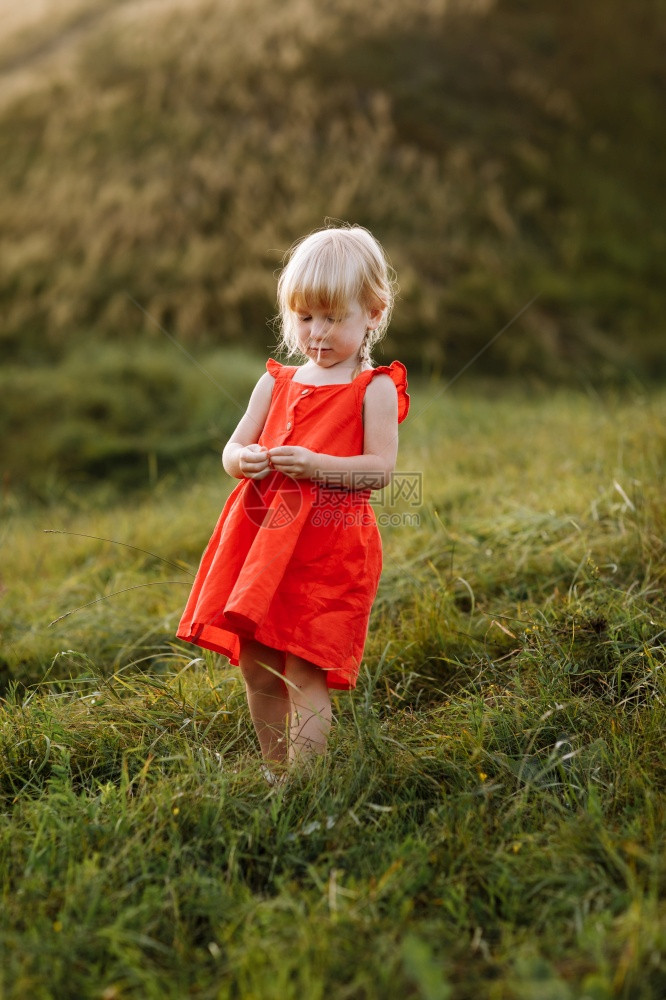 一个穿着红衣服的漂亮女孩在花园里玩图片