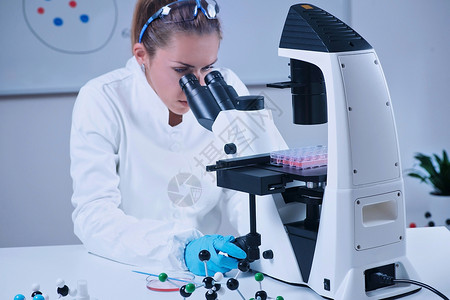女科学家通过显微镜观察图片