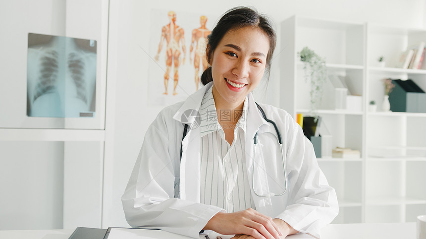 充满自信的年轻亚洲女医生身穿白色疗服听诊器看着相机微笑图片
