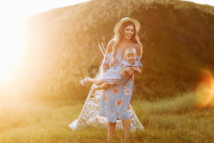 年轻母亲和小女儿在日落时田里玩得开心夏日时分在田里玩得开心母亲小女儿在户外玩得开心母亲节时快乐图片