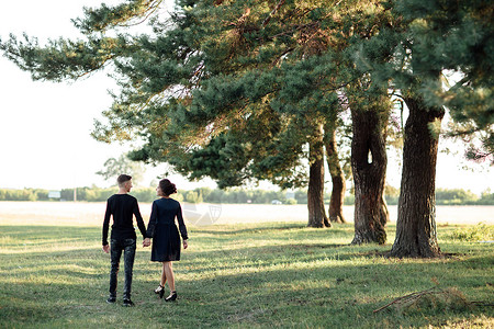 穿黑衣服的男女在户外约会浪漫关系情人节在夏日公园散步的年轻情侣手牵人节背景图片