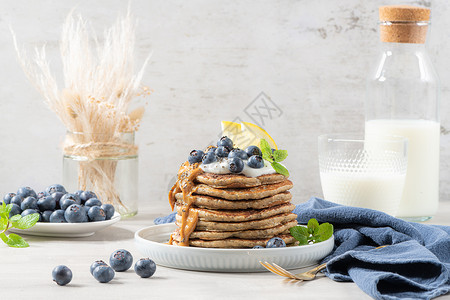 健康的夏季早餐自制的经典美式煎饼鲜蓝浆果柠檬酸奶和花生酱早安灰色石头背景背景