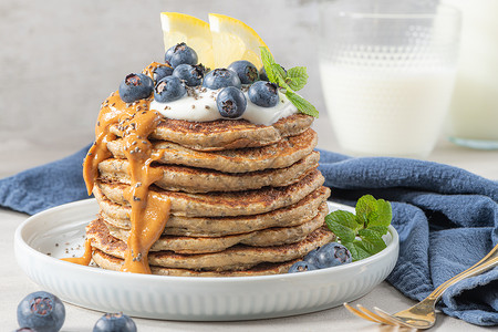 健康的夏季早餐自制的经典美式煎饼鲜蓝浆果柠檬酸奶和花生酱早安灰色石头背景背景