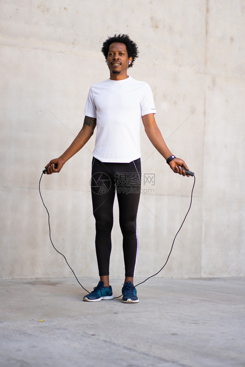 非洲运动员带着耳机在户外跳绳锻炼图片