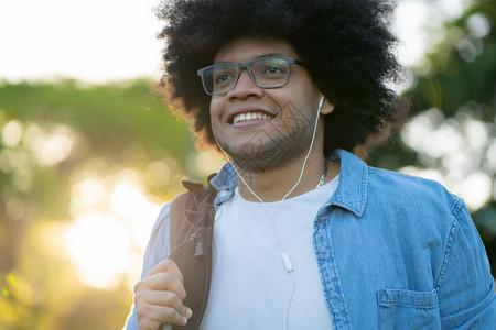 在街上走户外时用耳机听音乐的年轻拉丁男子肖像图片