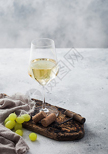 一杯白自制葡萄酒配有软木和板上的葡萄配有浅桌底布高清图片
