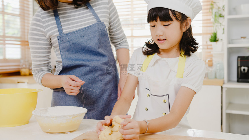 有学龄前孩子的年轻亚洲日本家庭早上在现代厨房吃早餐时有愉快的烹饪烤糕饼或派图片
