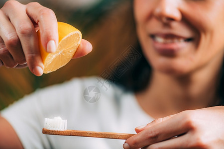 妇女在牙刷上挤柠檬和烘烤苏打混音图片