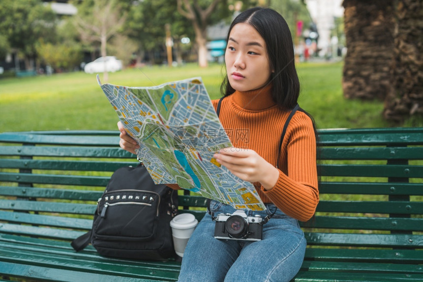 坐在公园长凳上看的亚洲年轻女肖像旅行概念户外图片