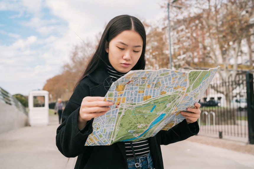 年轻亚洲旅行者女肖像她拿着在街上户外寻找方向图片