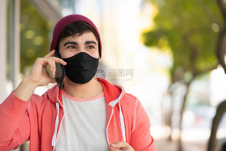 年轻人在街上户外散步时在电话上说的肖像男人戴面罩城市概念图片
