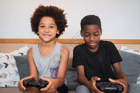 两个非裔美国人兄弟在家里玩电子游戏的肖像生活方式和技术概念图片