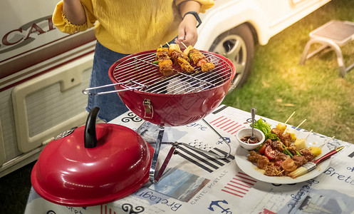 朋友做烧烤BBQ在大自然的热火上烧烤晚的宴背景