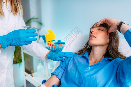 女人在抽血后感觉不舒服护士给她一杯水抽血和分析图片