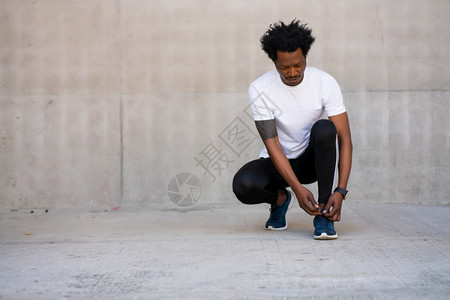 非洲运动员绑着鞋带准备户外工作图片