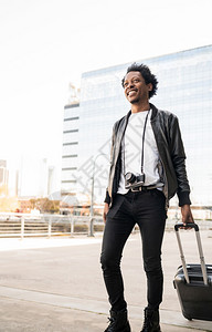 在街上户外行走时携带手提箱的Afro旅游男子的肖像图片