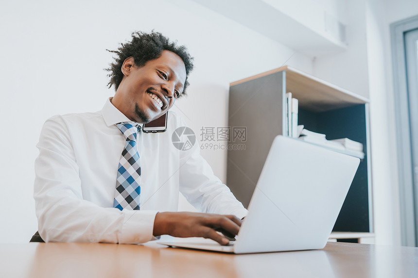 专业商人在办公室工作时电话上交谈和使用笔记本电脑图片